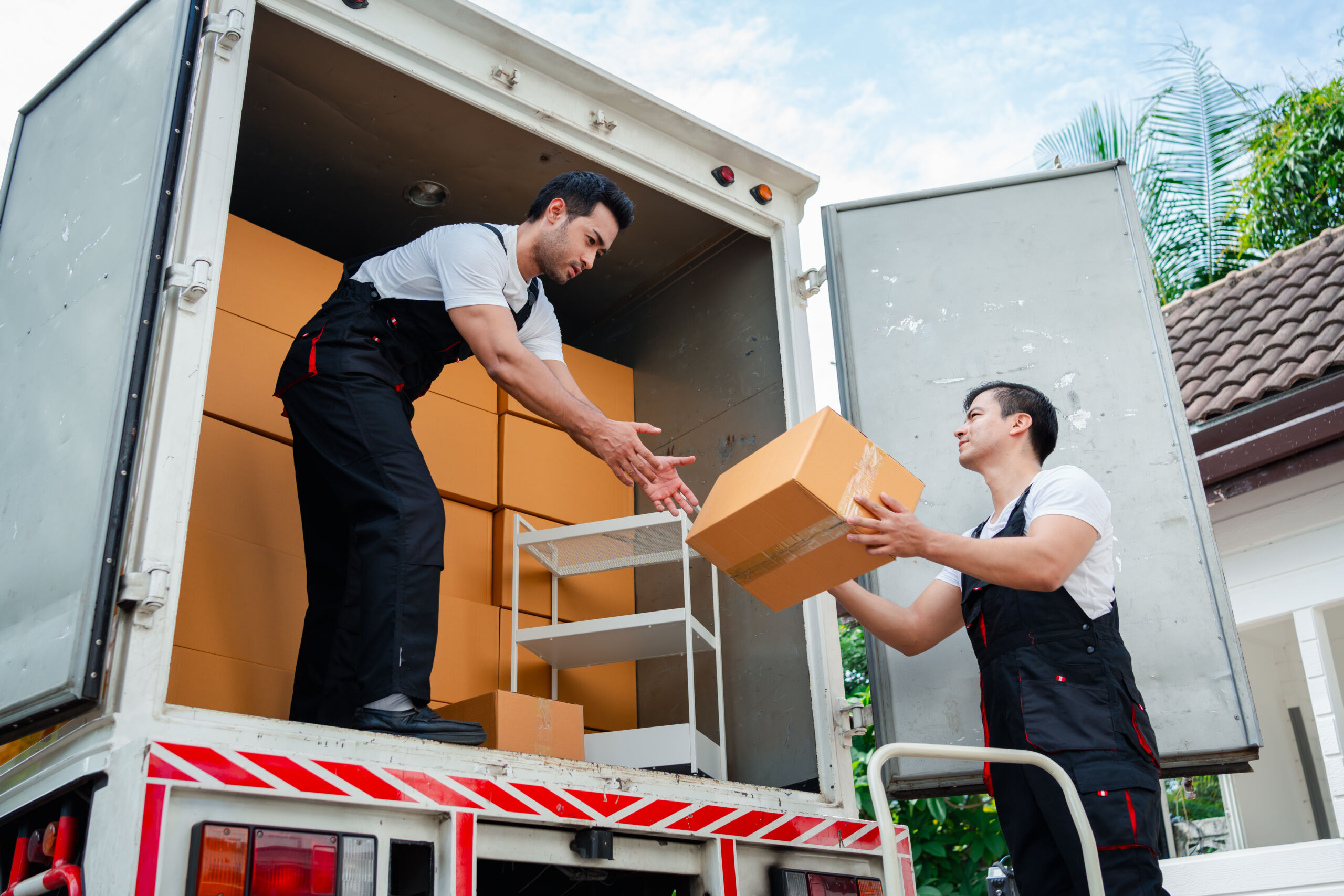 Unloading boxes and furniture from a pickup truck to a new house with service cargo two men movers worker in uniform lifting boxes. concept of Home moving and delivery.